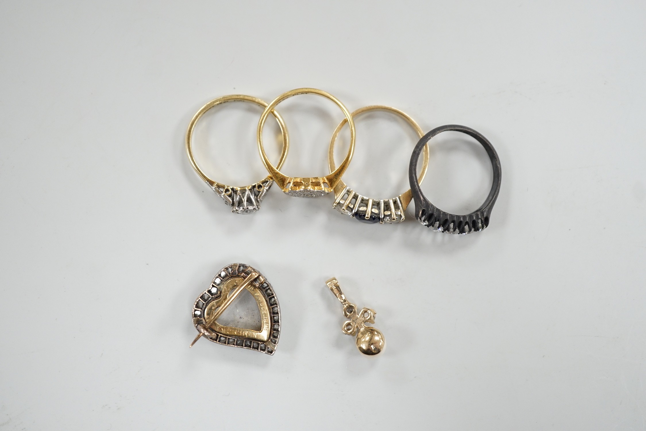 An 18ct, plat and single stone diamond ring, with diamond set shoulders, size O, a similar diamond cluster ring, size N, a blackened? 18ct gold and five stone diamond ring, a late Victorian diamond set heart shaped mourn